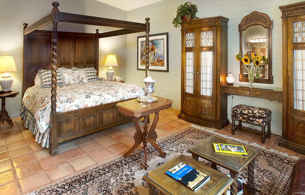 A cozy bedroom featuring a four-poster bed and a stylish table, creating an inviting and elegant atmosphere.